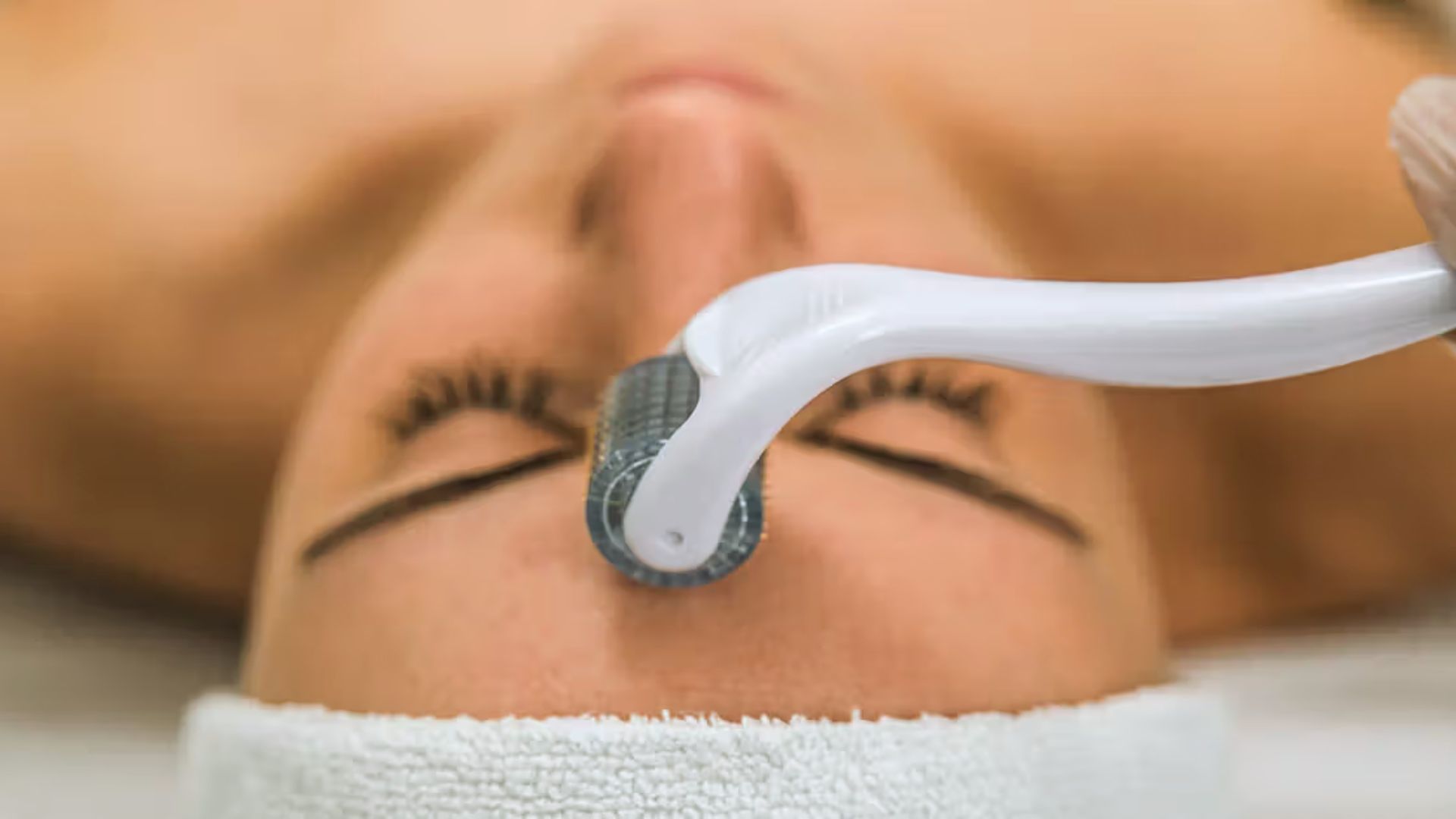  A woman having her eyebrows waxed, with a brush being used for the application process.