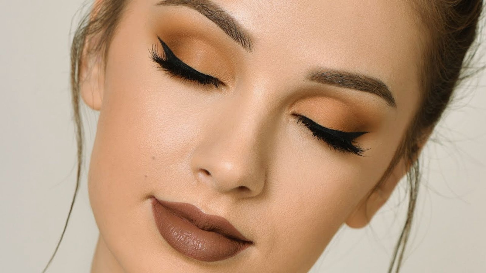 A woman with brown eyes and makeup, showcasing a polished and elegant appearance.