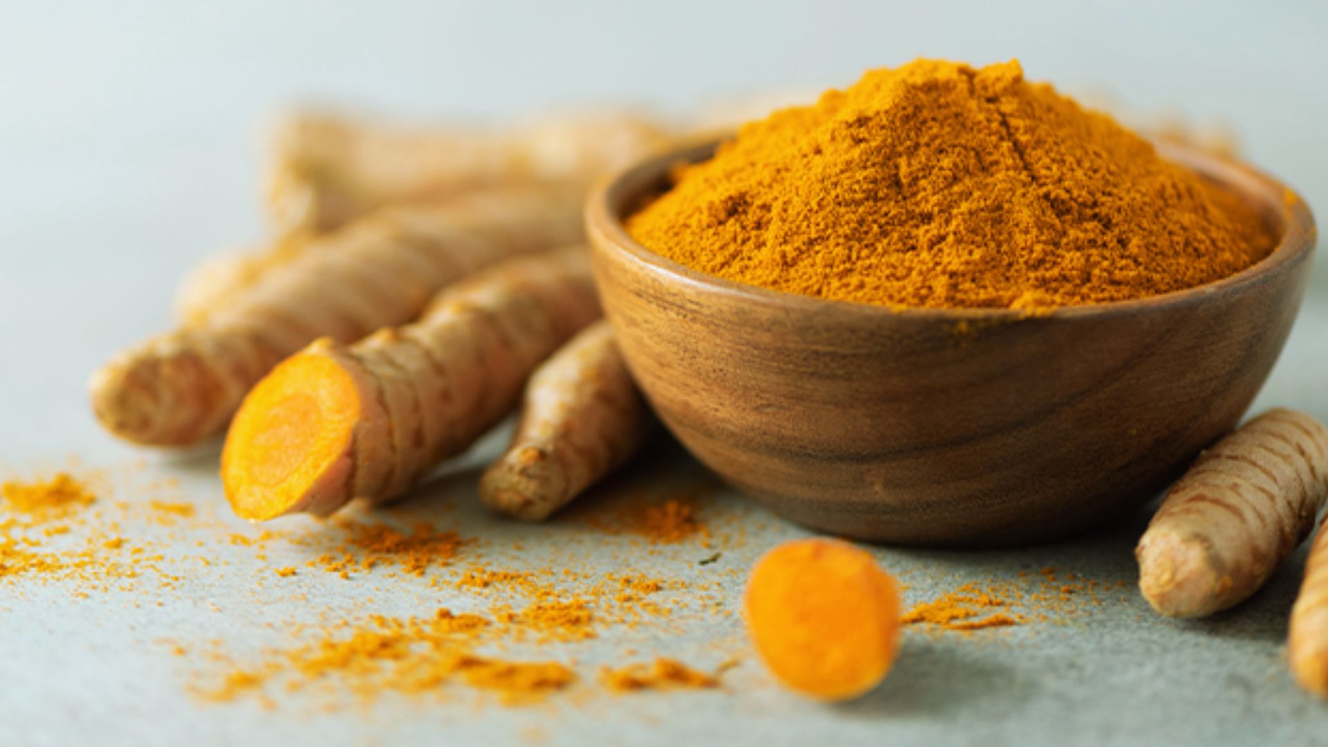 Turmeric powder in a rustic wooden bowl, showcasing its vibrant yellow color and fine texture.