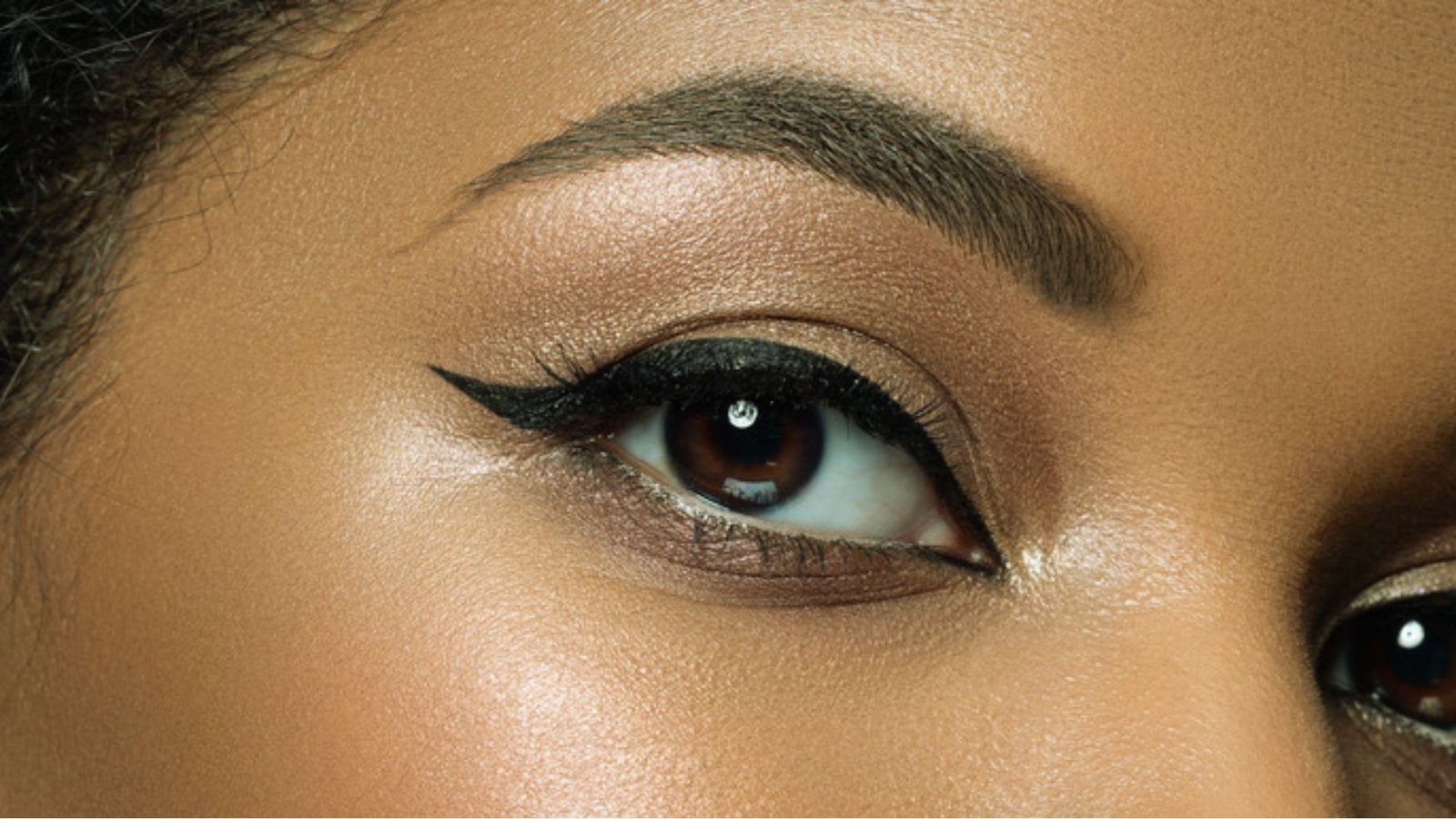 Close-up of a woman's eye adorned with dark black eye shadow, highlighting her eyelashes and eyelid contours.
