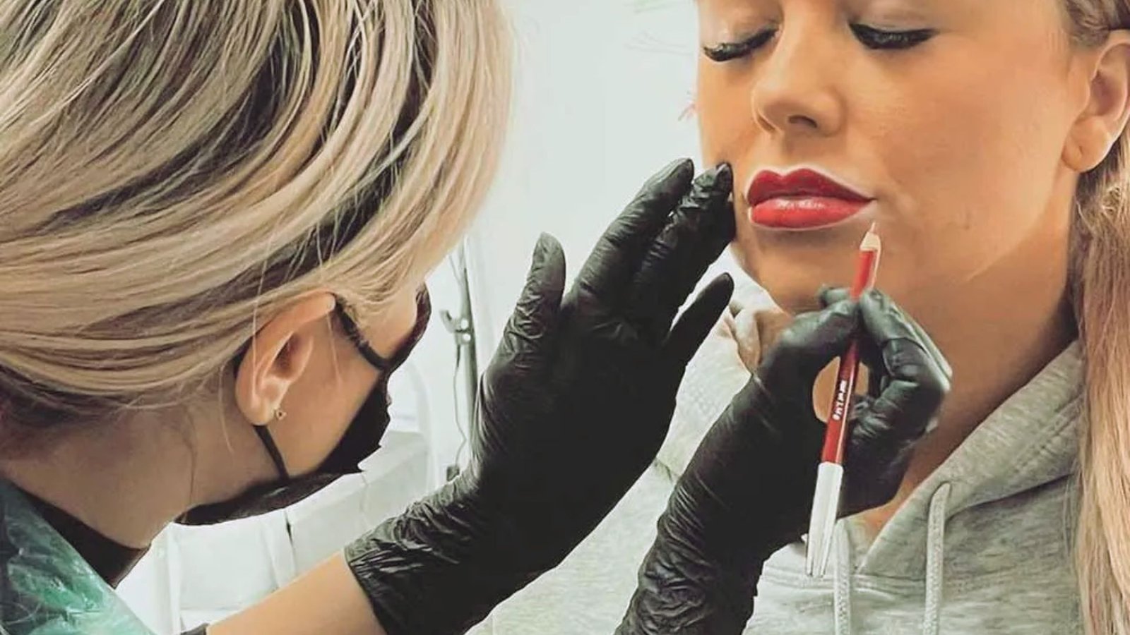 A woman receiving lip enhancement treatment from a male practitioner in a clinical setting.