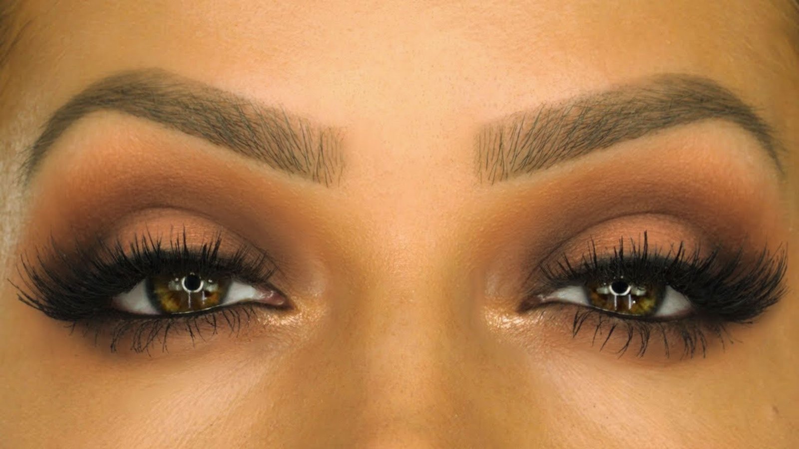 Close-up of a woman's eyes showcasing long, elegant lashes against a soft, blurred background.
)
