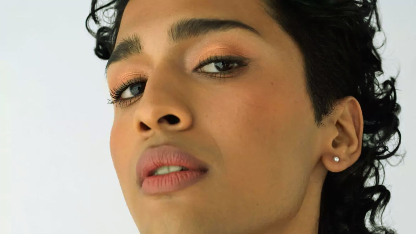 Close-up of a man with curly hair, showcasing his facial features and expression.