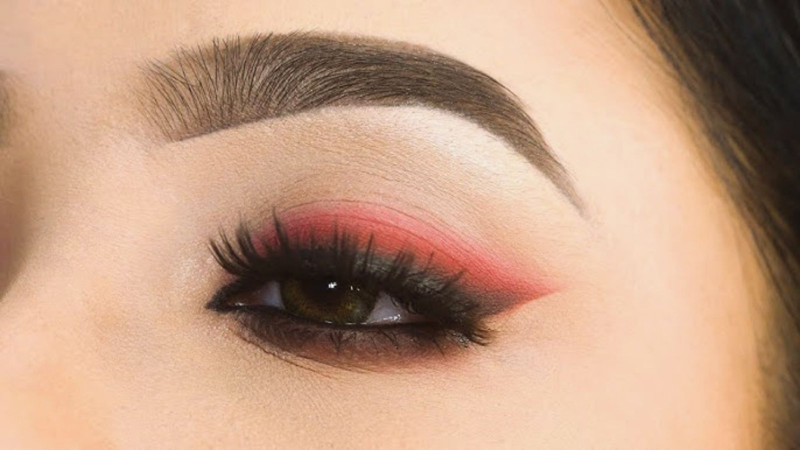 A woman showcasing striking black and pink eye makeup, emphasizing her bold and artistic style.