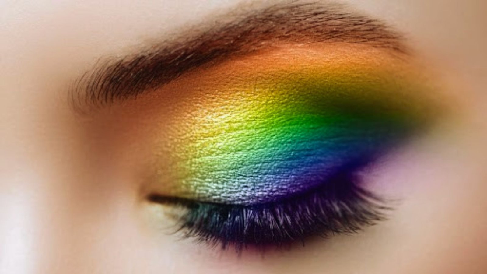 Vibrant rainbow eye shadow applied to eyelids, showcasing a creative and colorful beauty makeup concept.