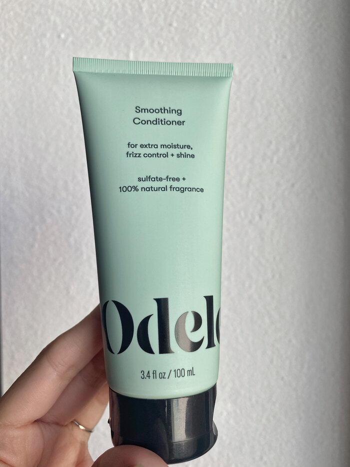 holding up conditioner bottle against white wall