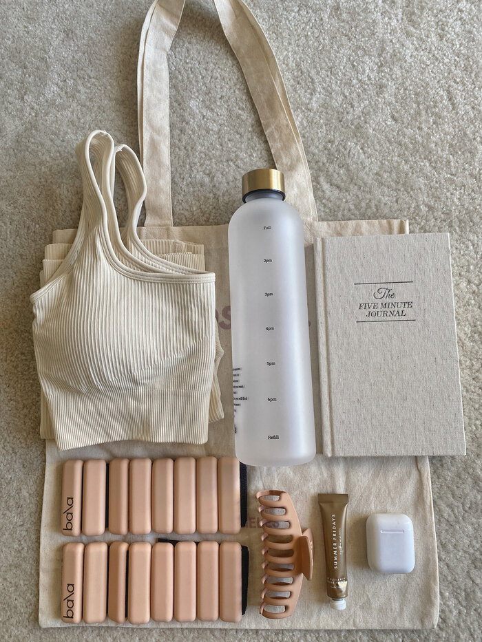 self care items flatlay of journal water bottle and weights