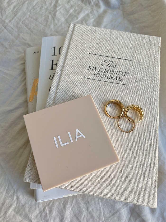 five minute journal with gold rings and makeup flatlay