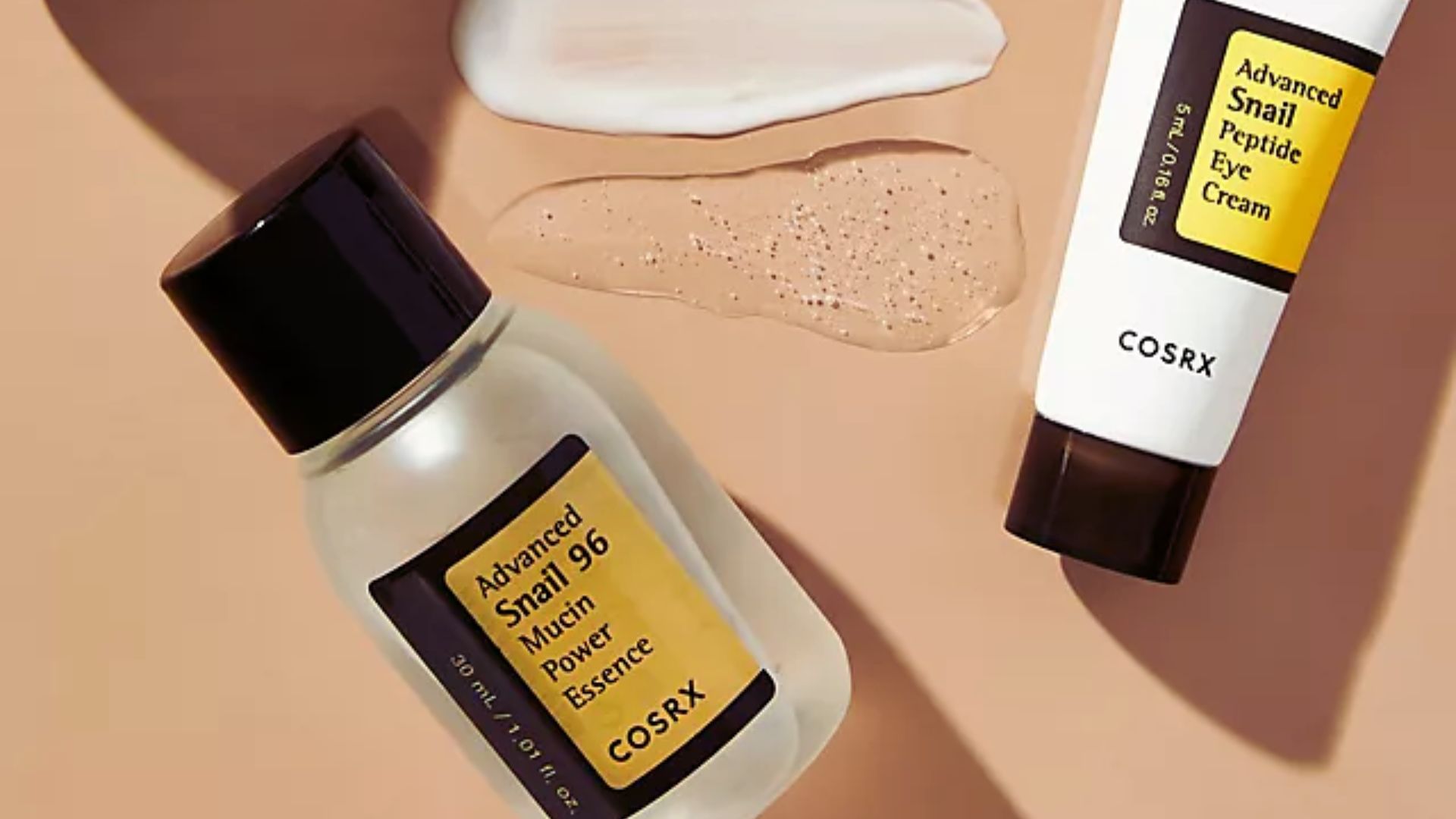 Cosmetic products on a beige background: a bottle of COSRX Snail Mucin Essence and a tube of Snail Peptide Eye Cream, with white cream and gel samples.