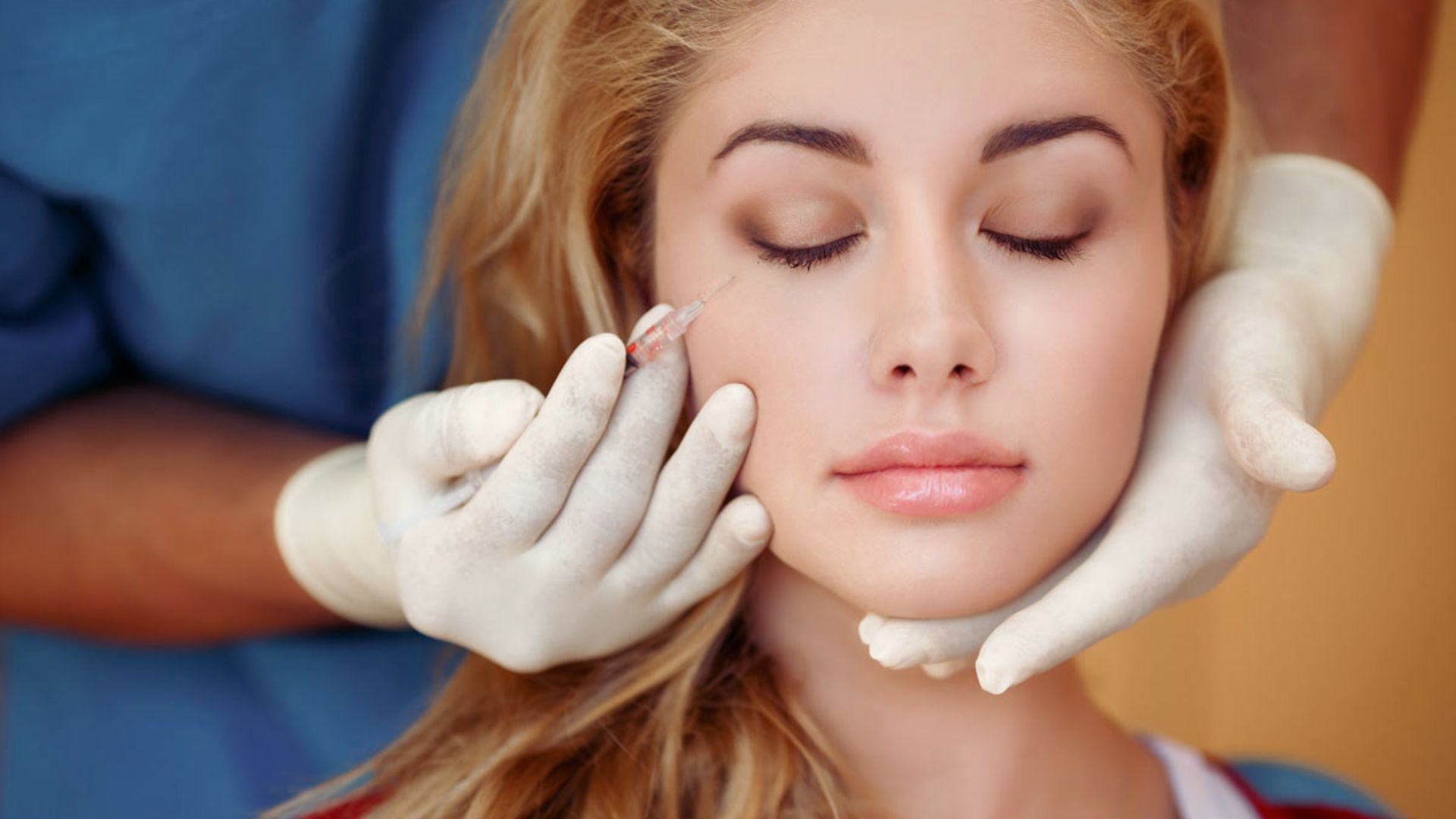 A woman receiving a facial treatment, relaxing on a spa bed with a serene expression and a therapist applying products.
