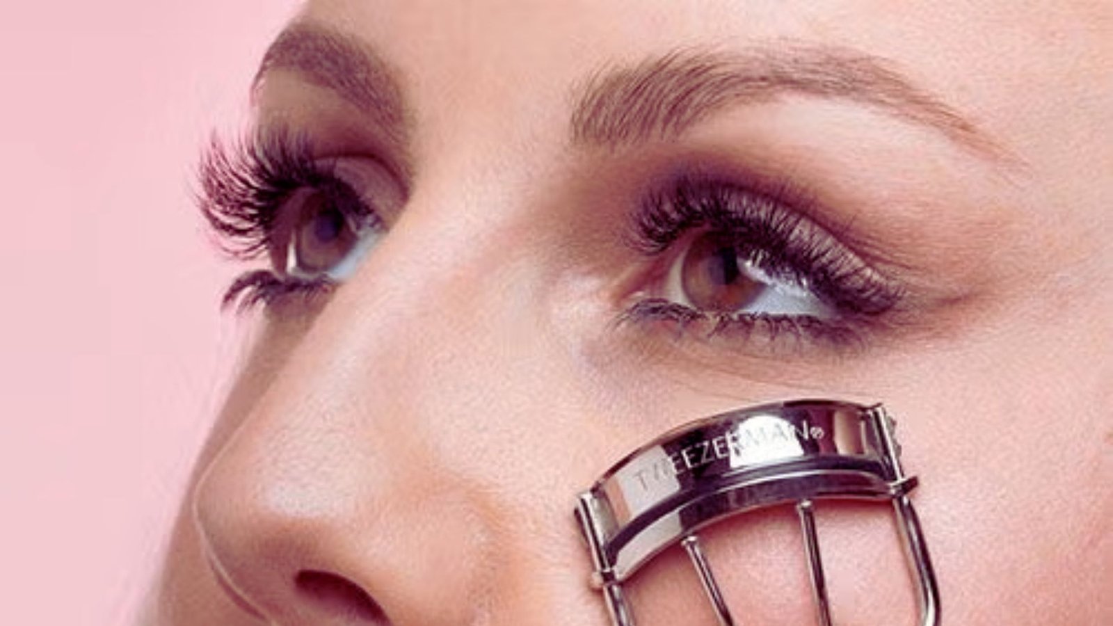 A woman holds a metal comb against her face, showcasing a unique and artistic expression.