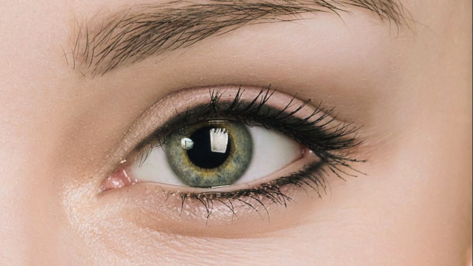 Detailed close-up of a woman's eye, highlighting her striking green iris and delicate eyelashes.