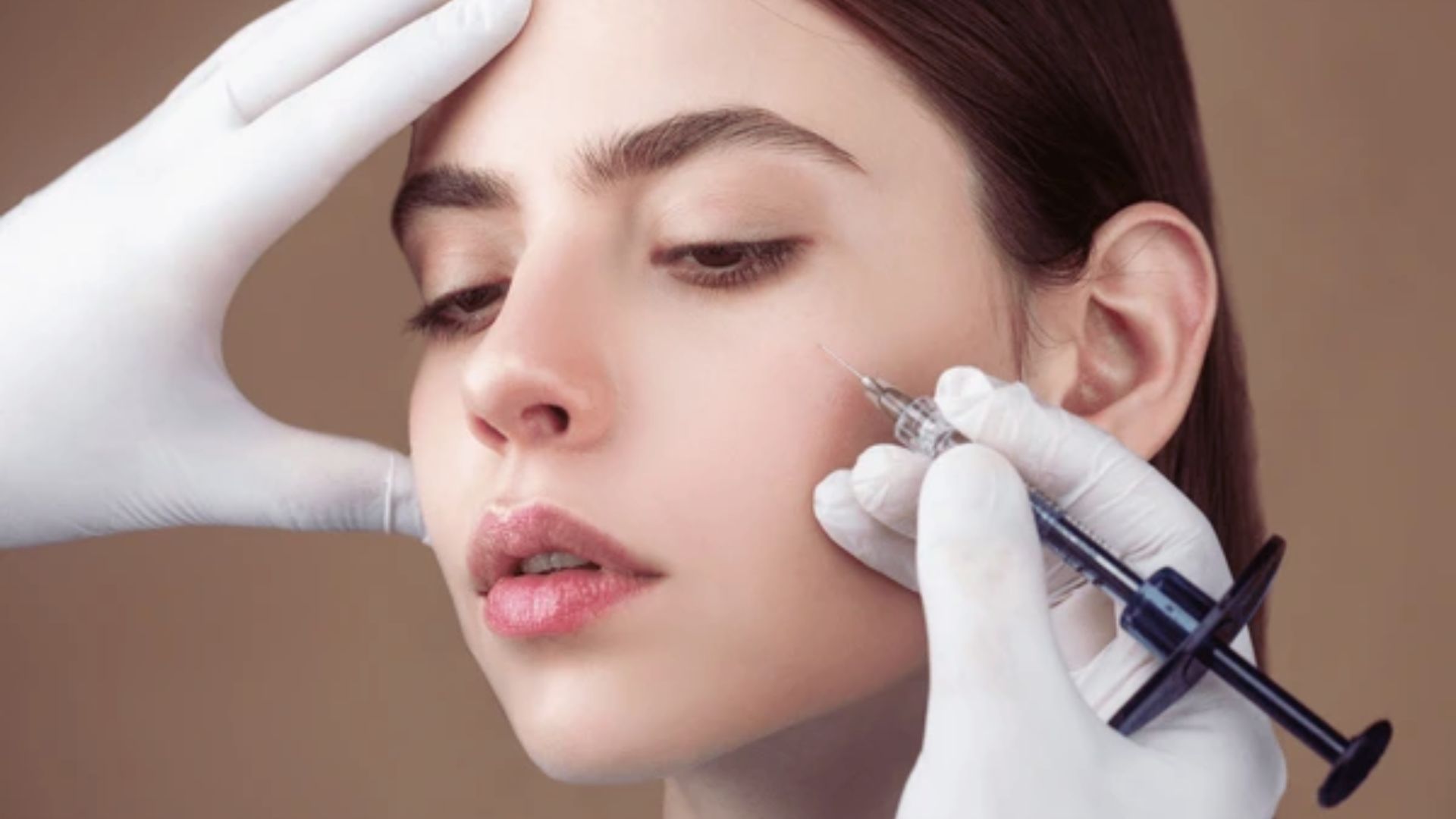 A person with closed eyes receives a facial injection from a gloved professional, conveying a clinical and focused atmosphere.