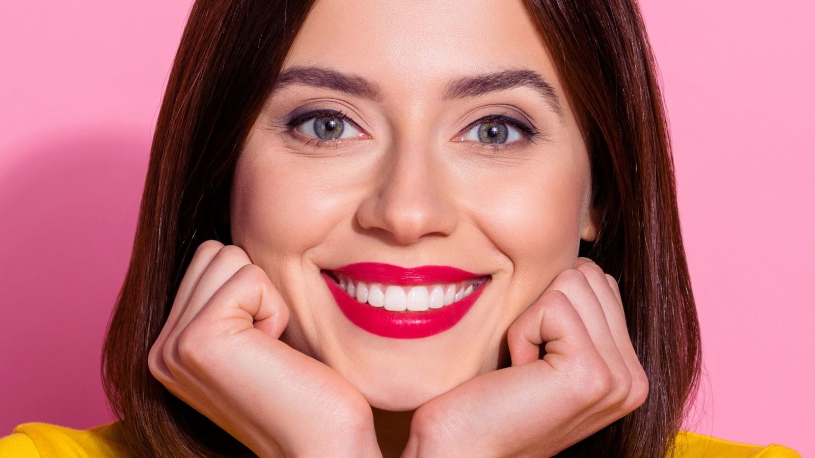 A smiling woman showcasing bright red lips, conveying joy and approachability.