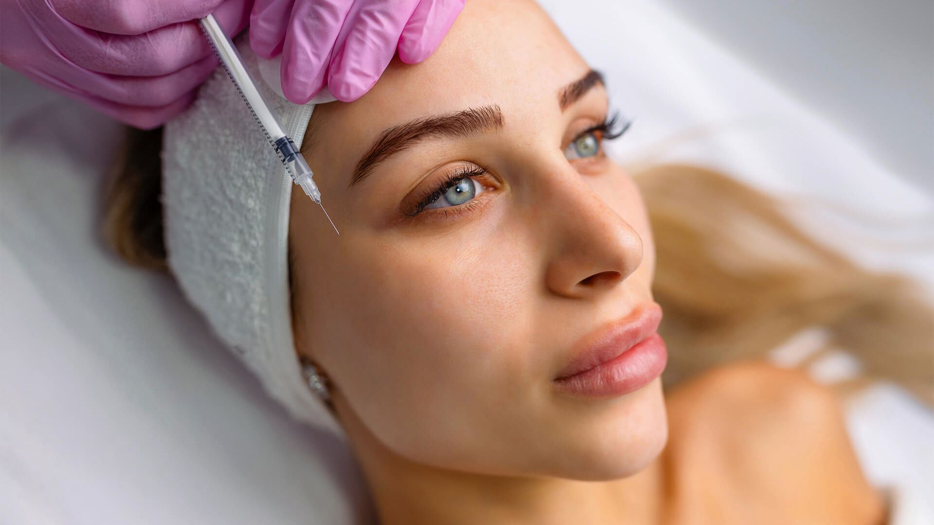  A woman relaxes while receiving a facial treatment at a spa, with soothing products applied to her face.