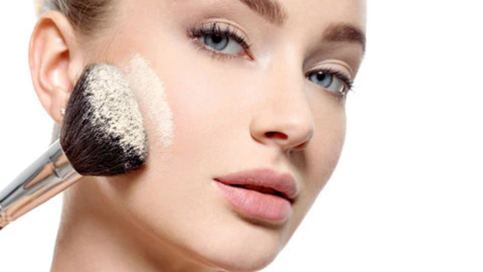 A woman applies powder to her face, enhancing her makeup with a focused expression.