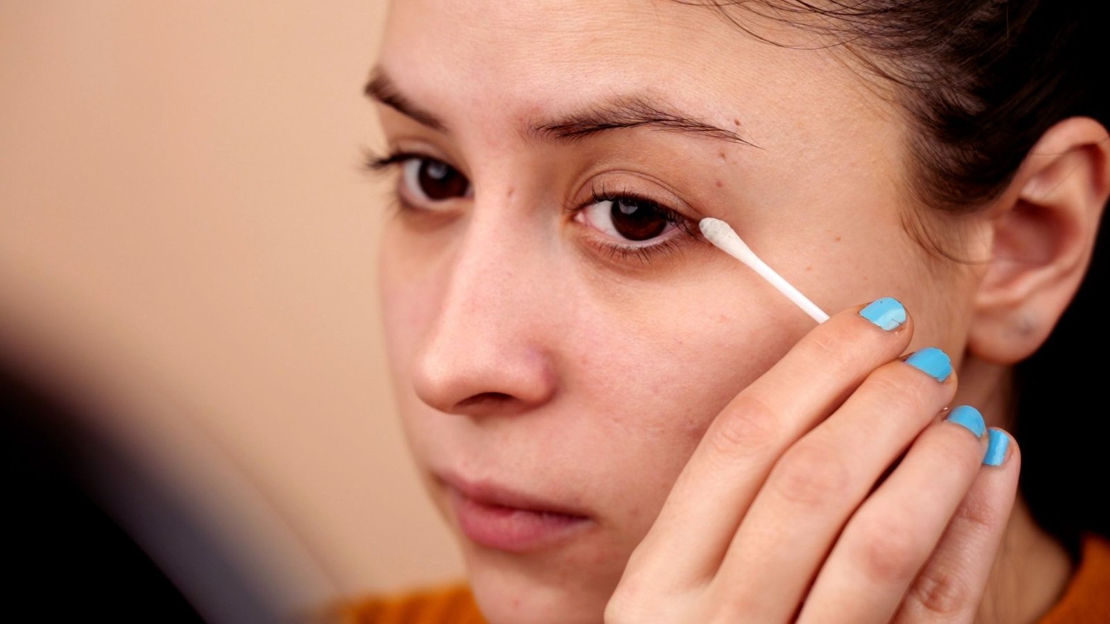 A woman applying makeup to her face, focusing on enhancing her features with various cosmetic products.