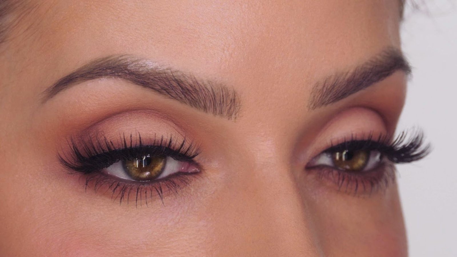 Close-up of a woman's eye showcasing long, elegant eyelashes against a soft, blurred background.