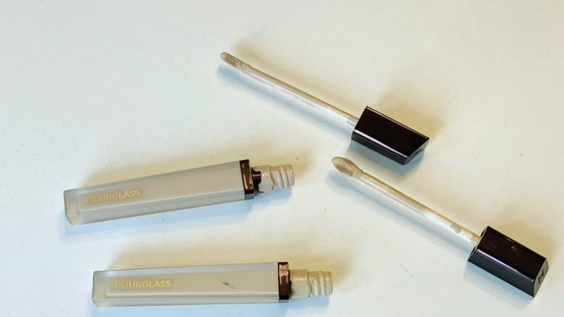 Three lip glosses in various shades arranged neatly on a white surface.