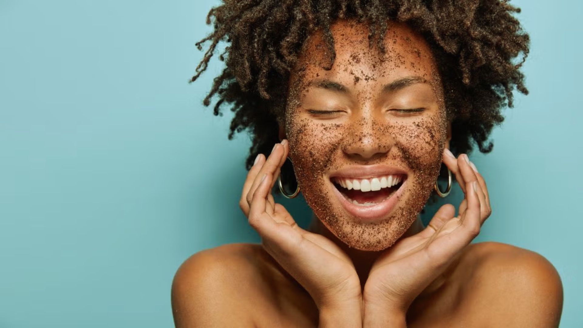 A woman with brown skin has a face covered in dirt, suggesting she has been working outdoors or in a rugged environment.