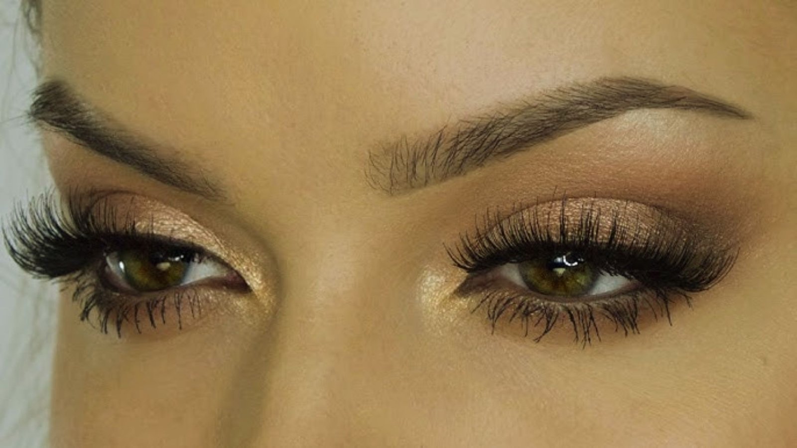 Close-up of a woman's eyes showcasing long, elegant lashes against a soft, blurred background.