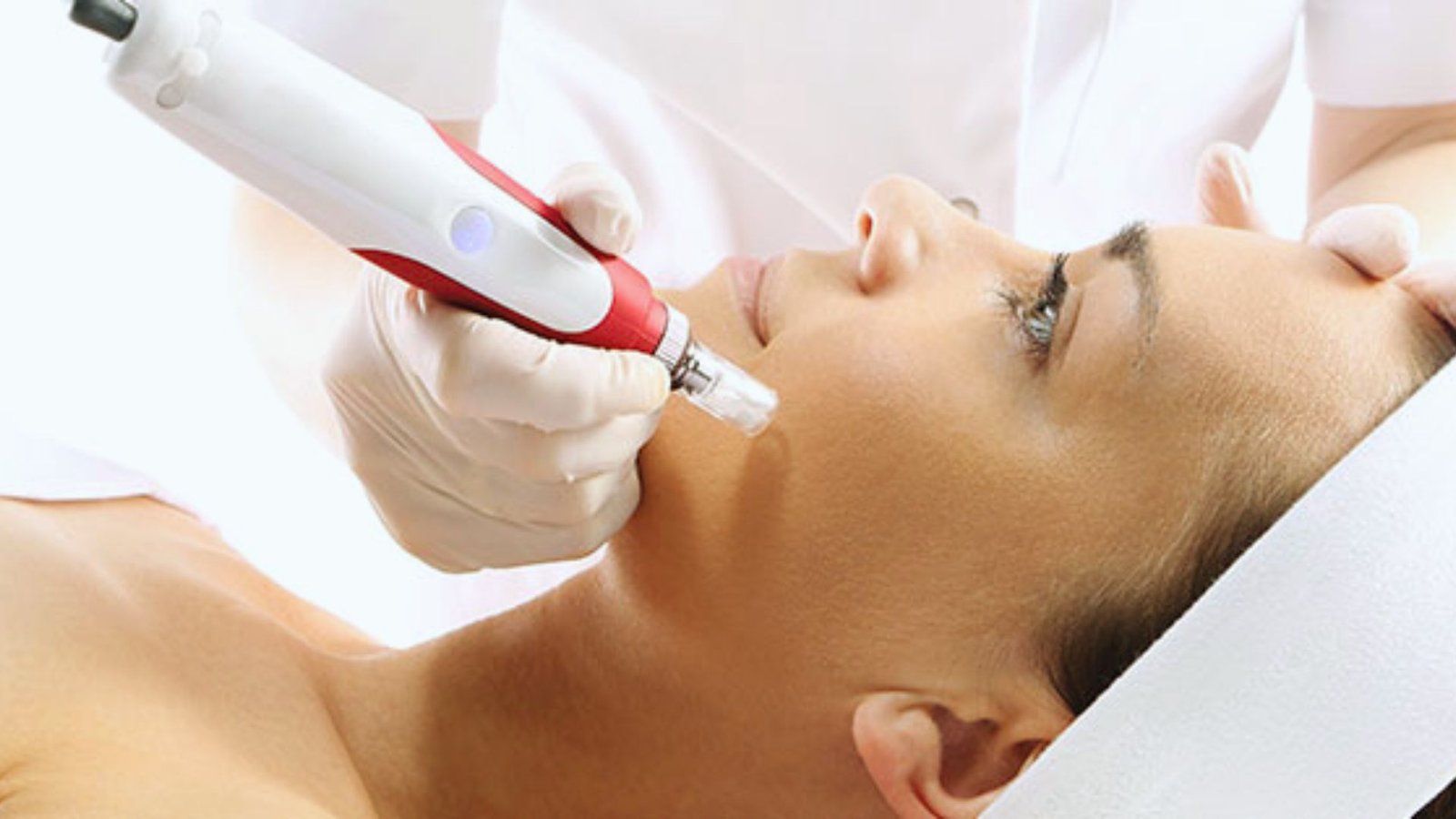 A woman receiving a facial treatment using a red and white device, focused on her skin care routine.