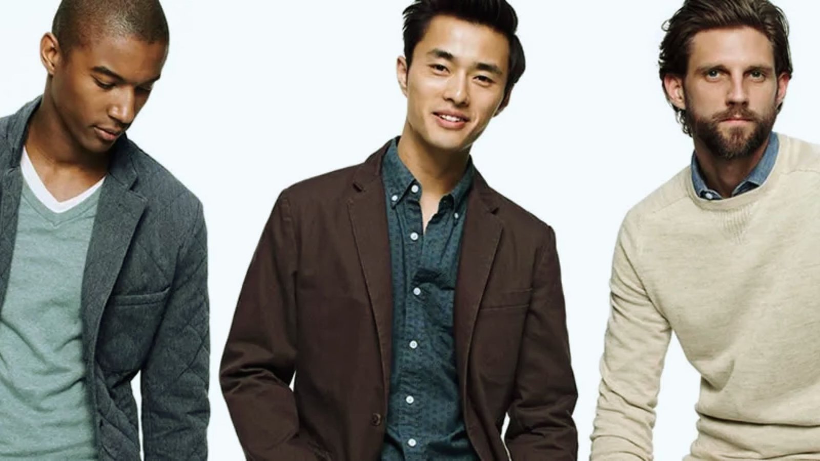 Three men dressed in jackets and sweaters, standing together in a casual setting.