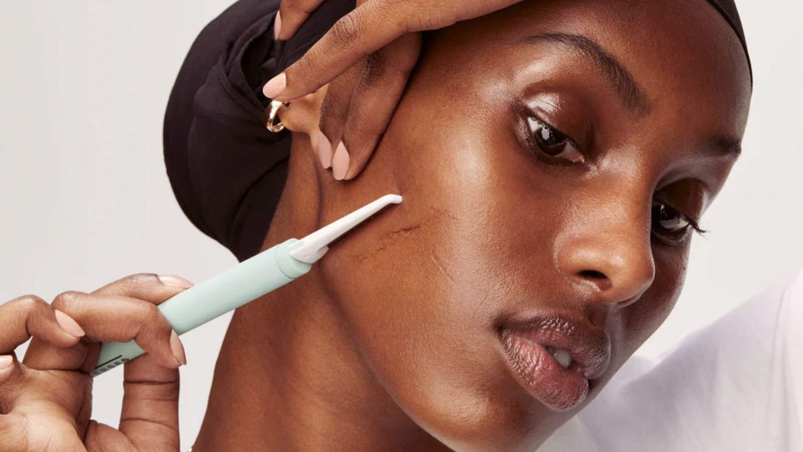 A woman gently brushes her skin, focusing on exfoliation and skincare in a bright, well-lit bathroom setting.