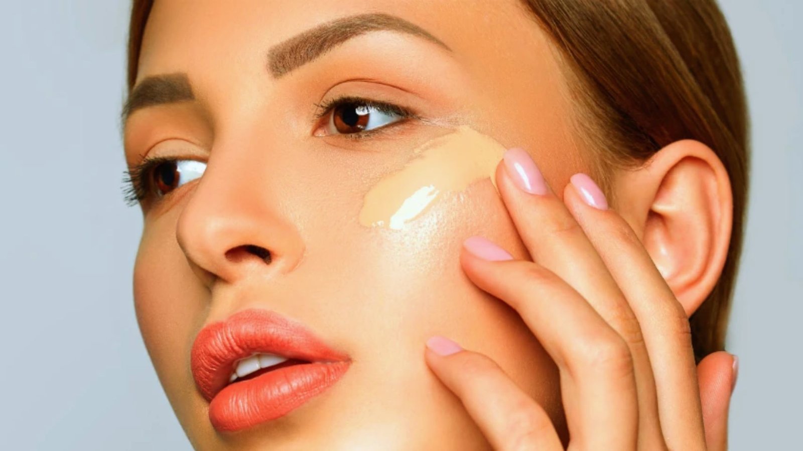 A woman applying cream to her face, showcasing a skincare routine.