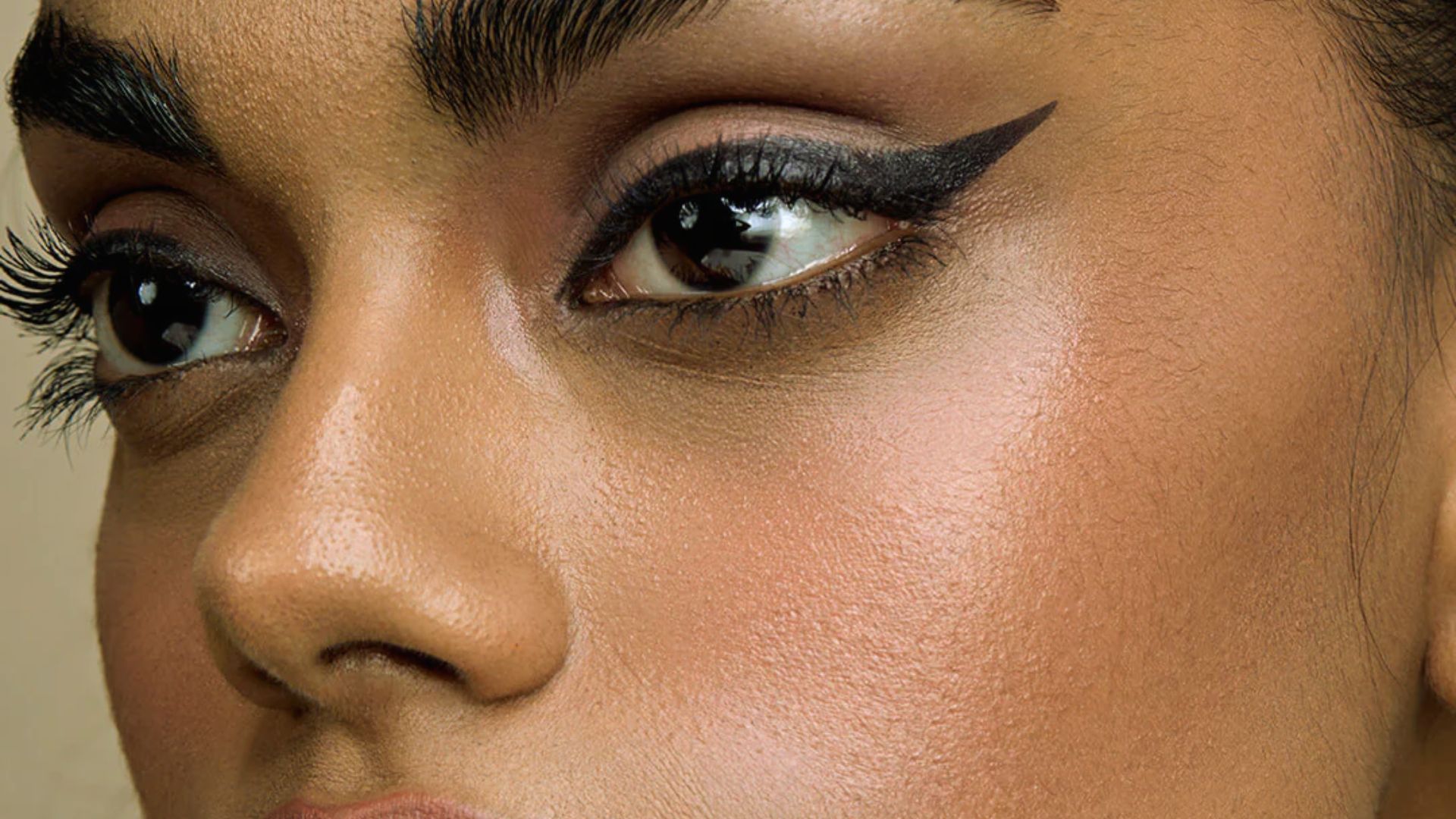A close-up of a woman's face showcasing her makeup, highlighting her eyes, lips, and flawless skin.