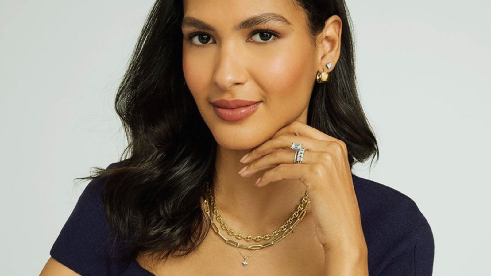 A woman wearing a necklace and a gold chain, showcasing her elegant style and accessories.