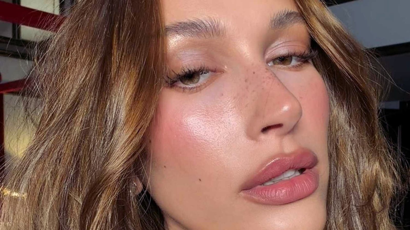 A woman with freckles on her face smiles softly, showcasing her natural beauty and warm expression.