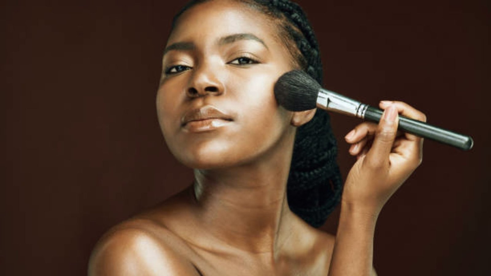 A woman applying makeup to her face with a brush, showcasing her beauty routine and artistic expression.