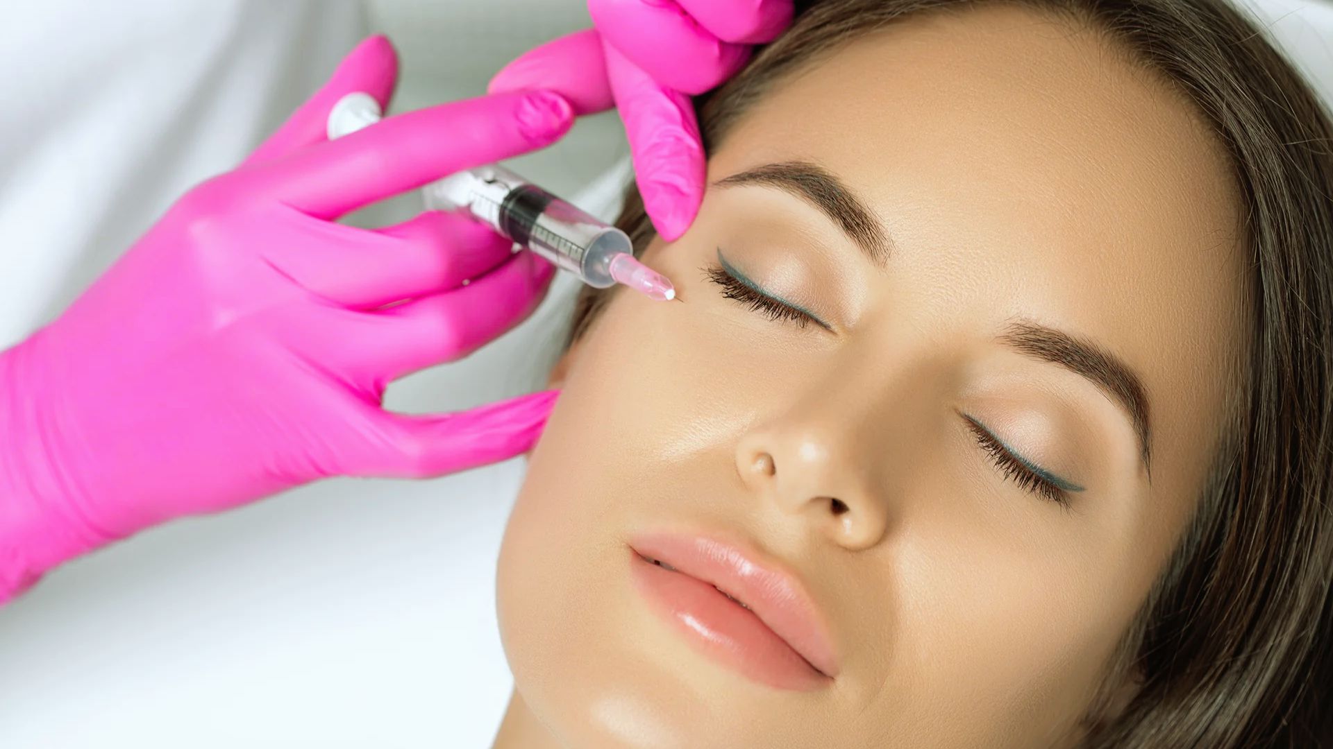A woman receiving an injection in her face, with a healthcare professional administering the procedure.