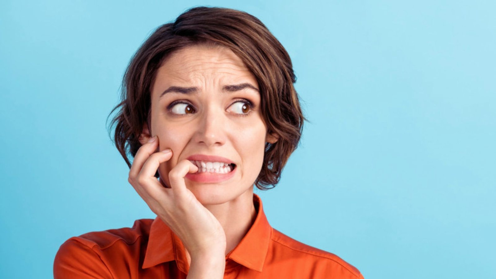 A surprised woman resting her chin on her hand, expressing astonishment with wide eyes and slightly parted lips.