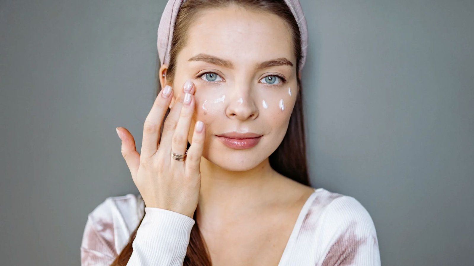 A woman wearing a white shirt and a white bandanna on her head, smiling softly at the camera.