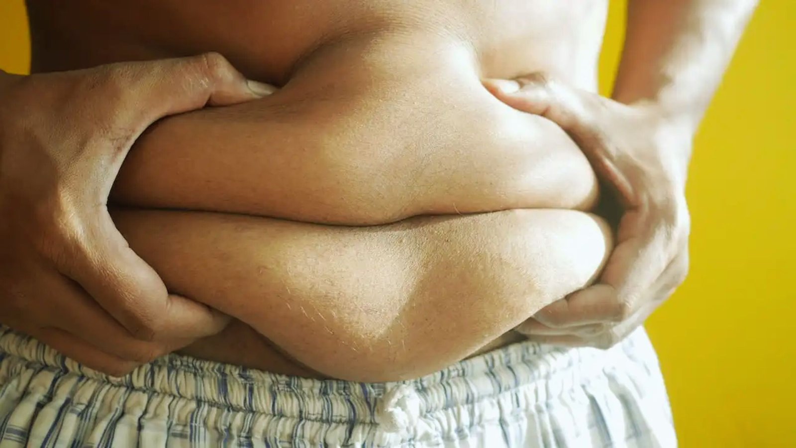 A man stands with his hands on his stomach, proudly displaying his belly.