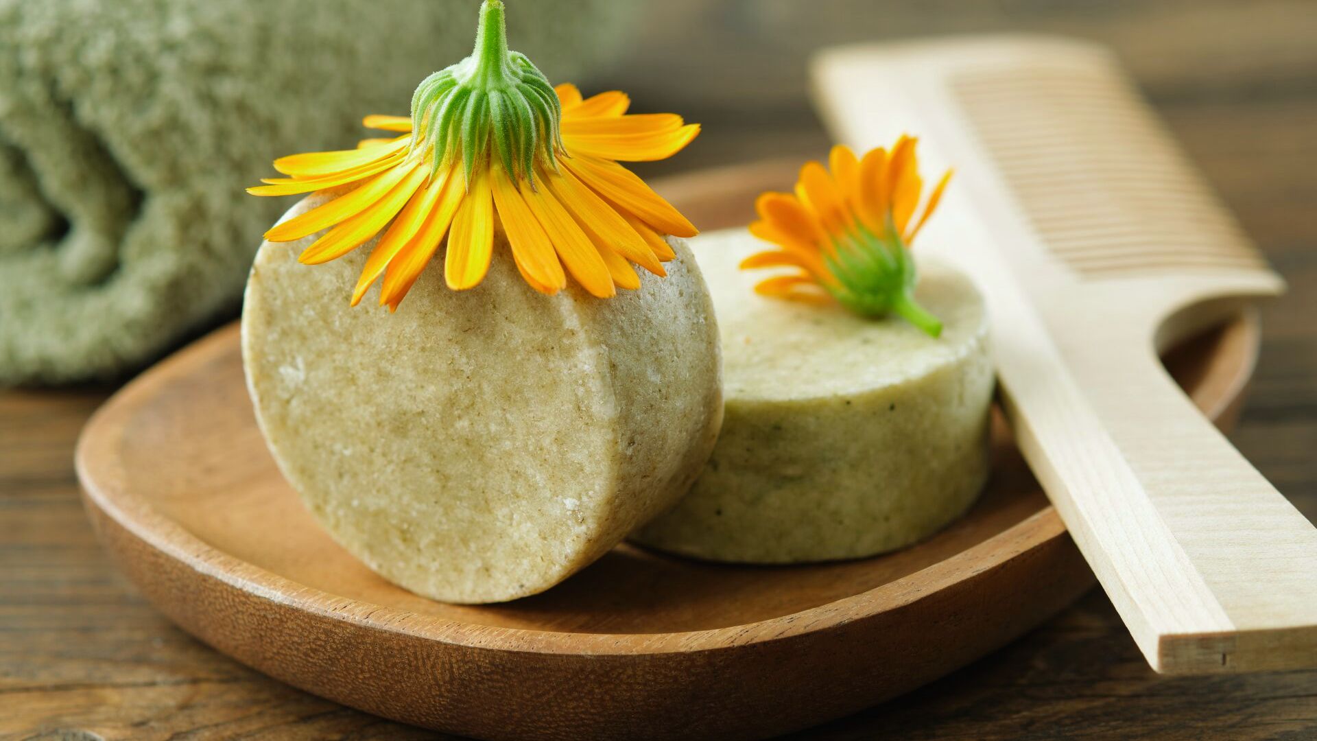 A wooden bowl containing soap and colorful flowers arranged artistically on top.