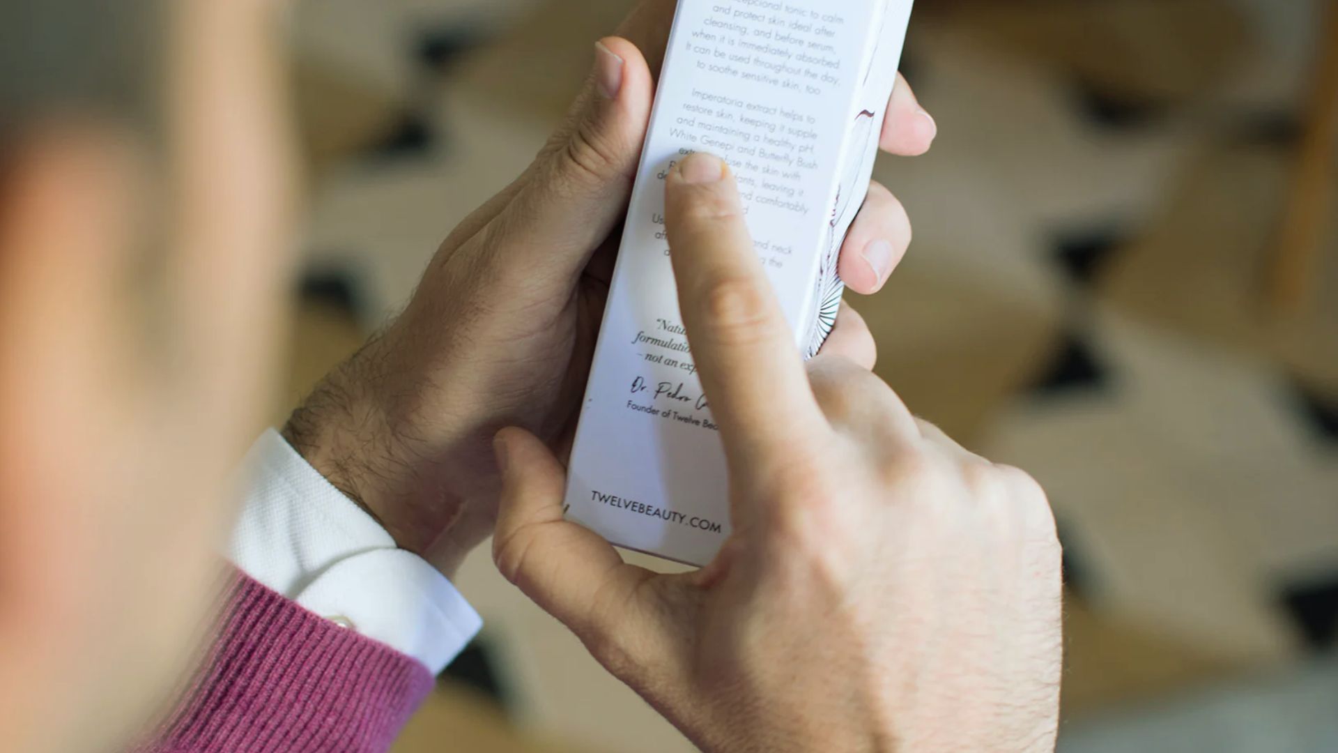 A man holds a book open, with his finger resting on the page, indicating he is reading or referencing the text.