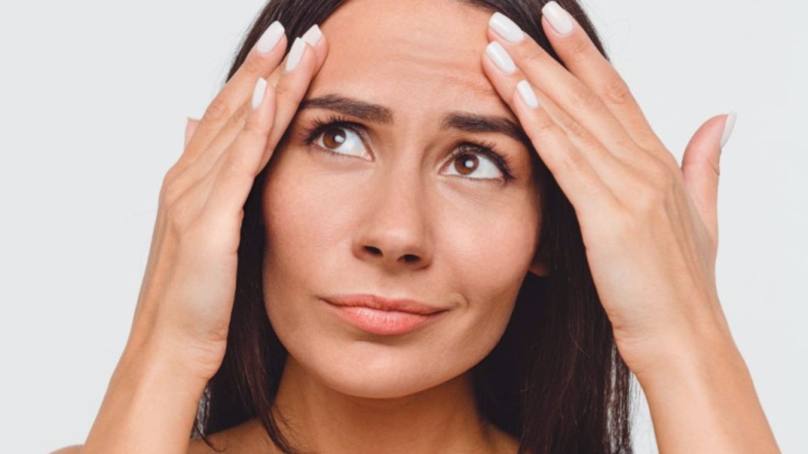 A woman sitting with her head in her hands, expressing distress or deep thought.