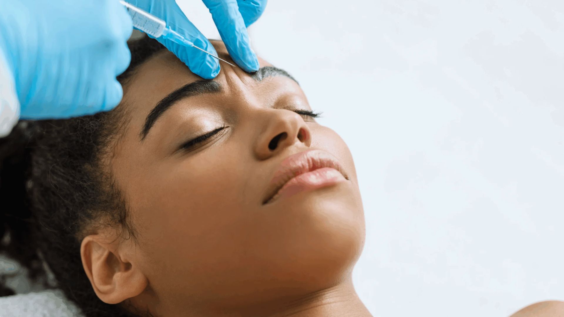 A woman receiving a facial treatment, relaxing on a spa bed with a serene expression and soothing ambiance around her.