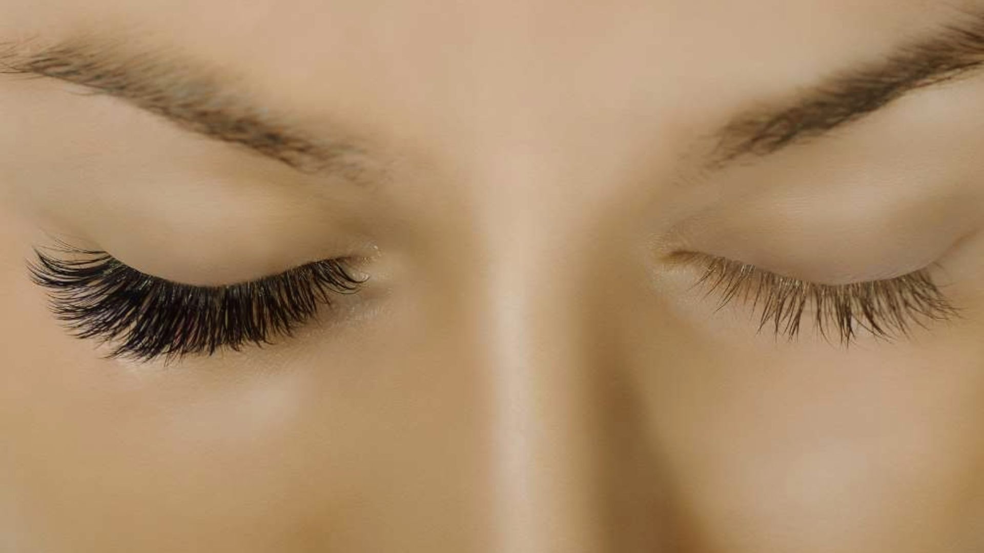Close-up of a woman's eyes showcasing long, elegant eyelashes against a soft background.